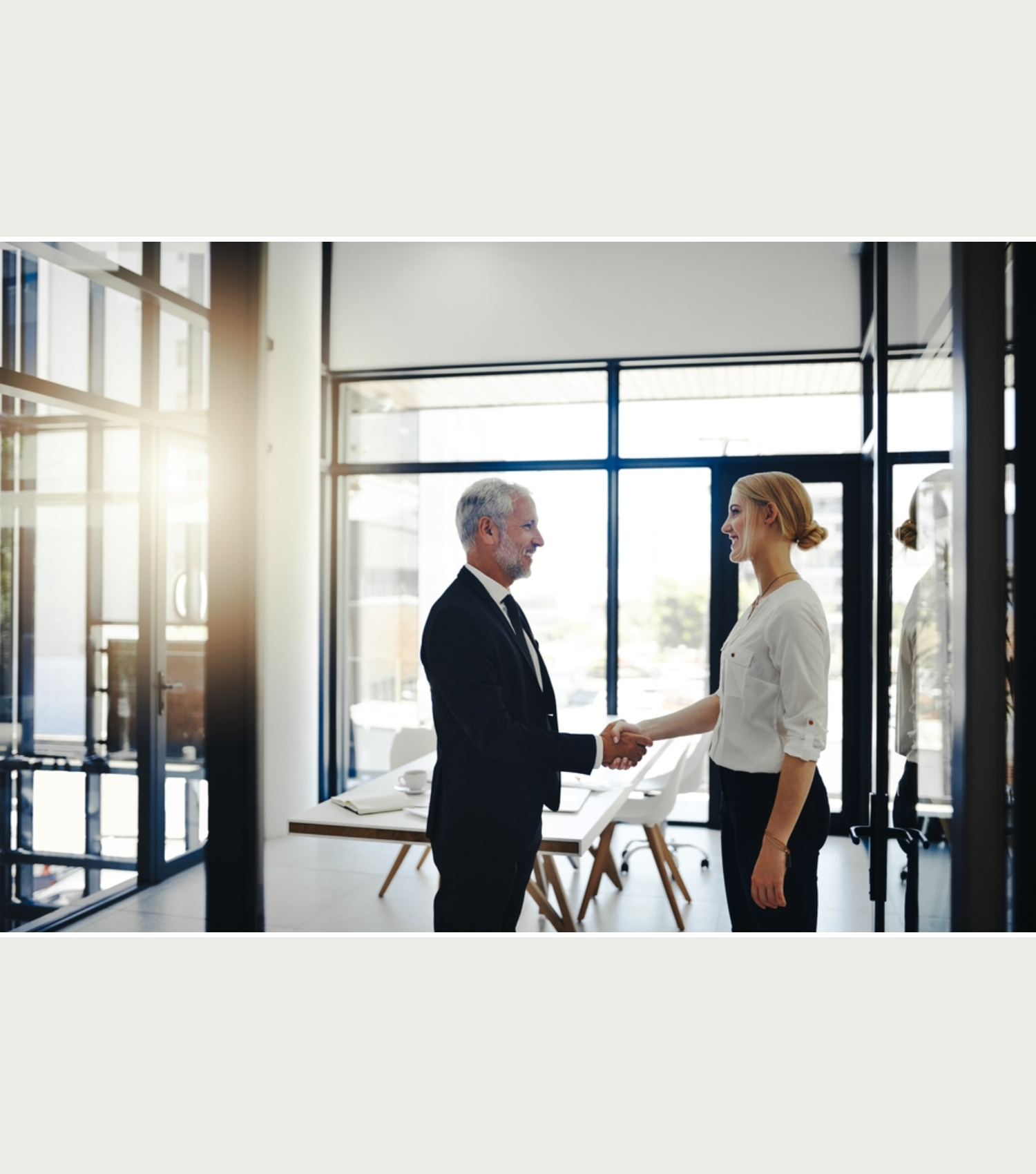 Two people shaking hands in an office.