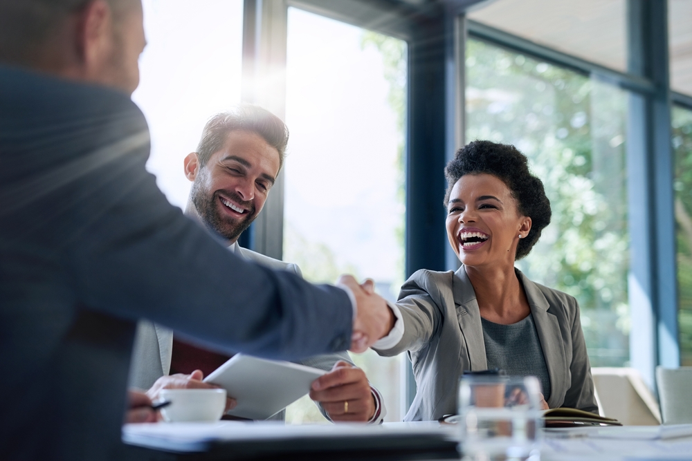 A businesswoman shakes hands with a businessman.