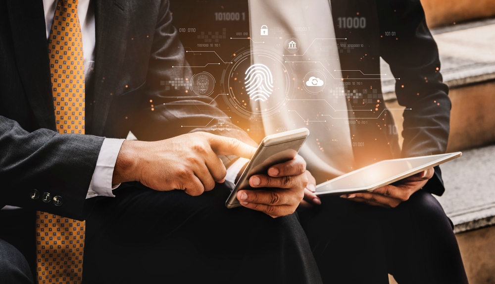 Photo illustration of two business men practicing cyber security on their devices.